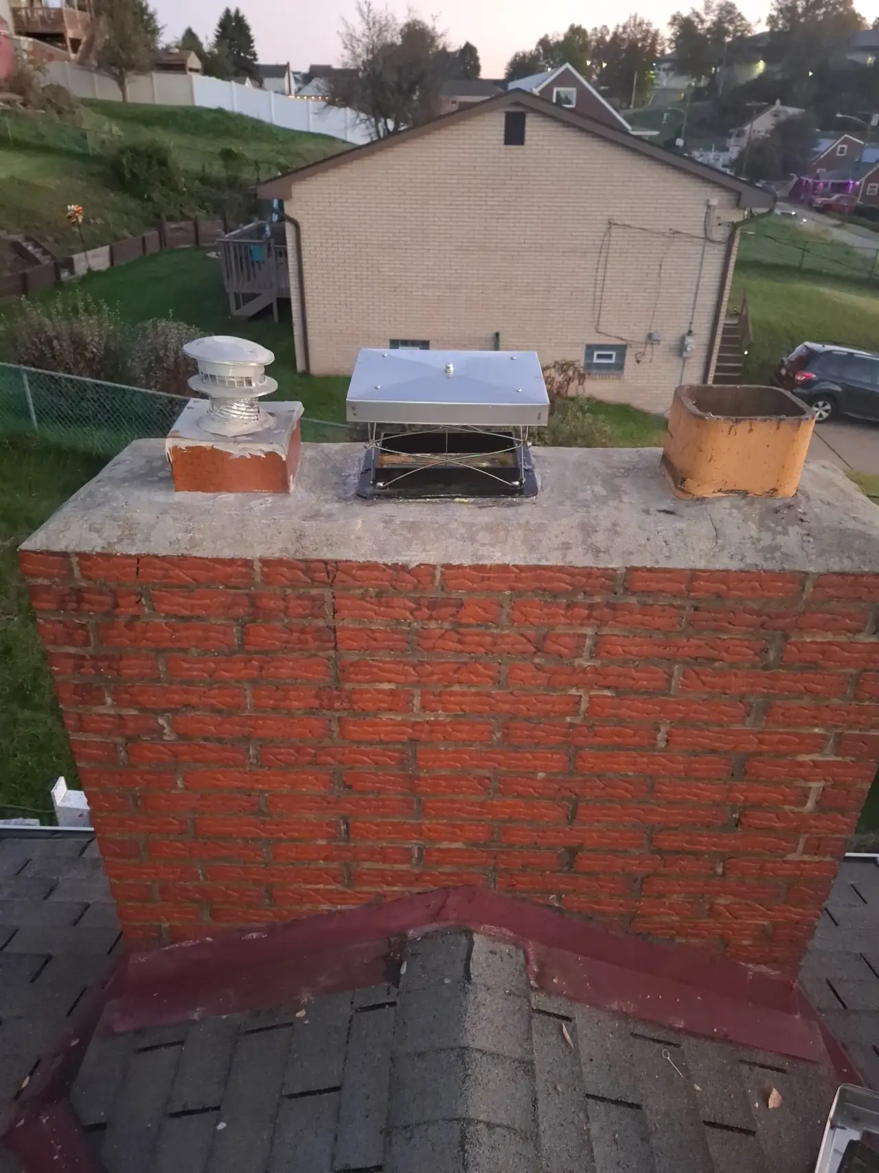The finished Allison Park, PA chimney with a new top-mount damper sealed to the crown over the newly lined fireplace flue, the gas vent cap at left and an open clay tile at right