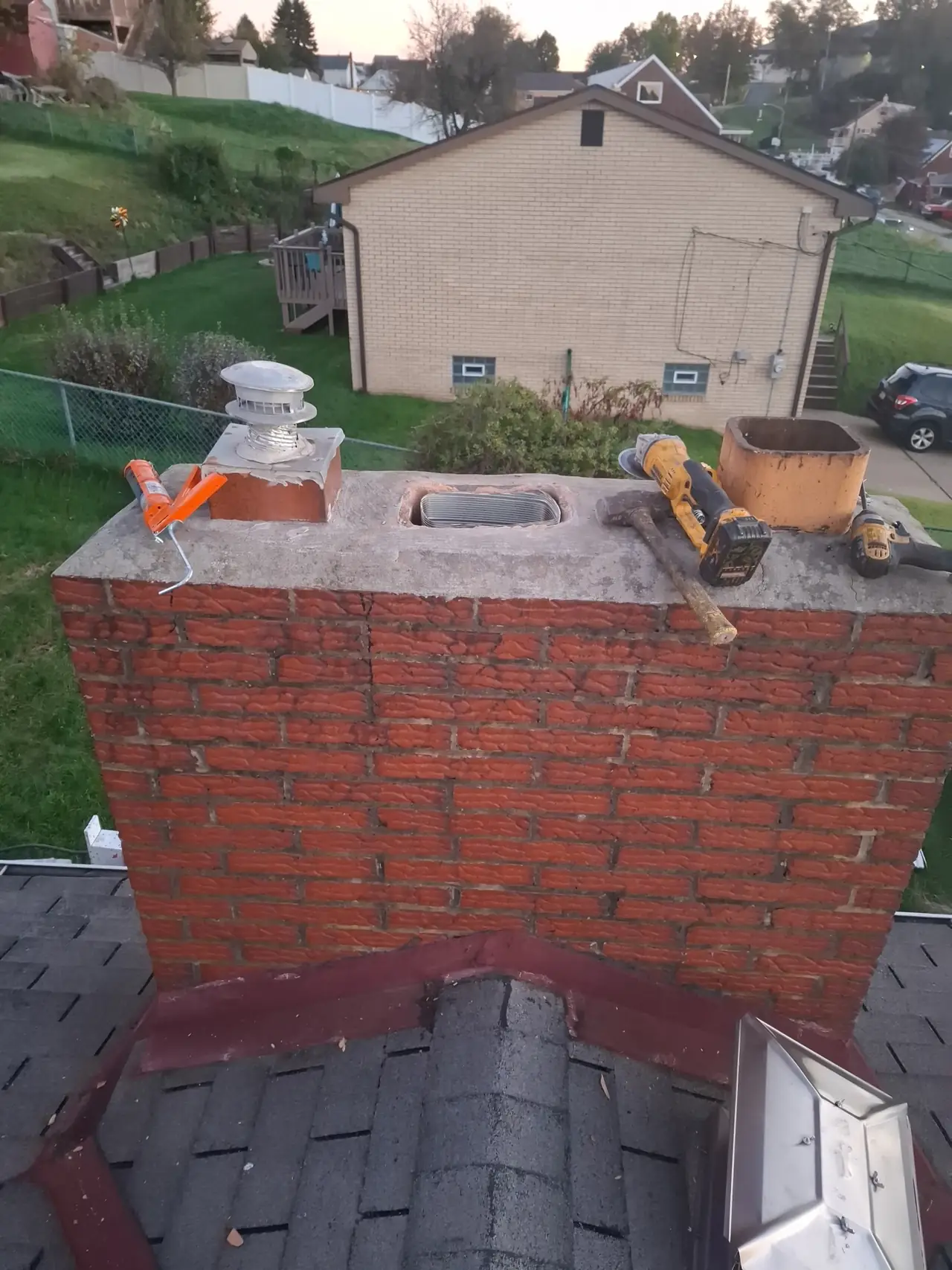 Stainless steel liner set down the center fireplace flue of a three-flue brick chimney in Allison Park, PA, tools still on the poured crown before the top damper went on